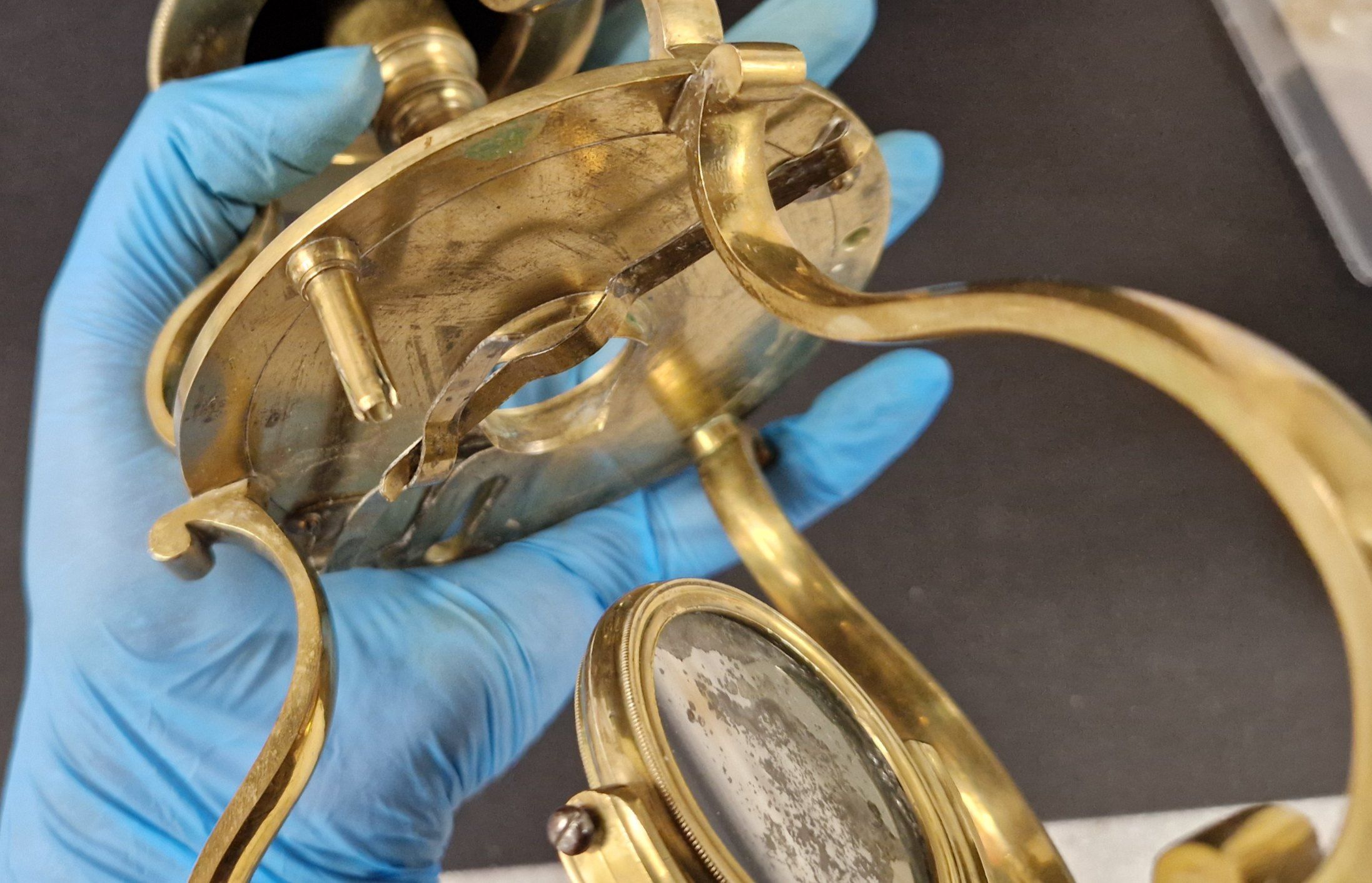 Élément en laiton d’un microscope tenu par une main gantée